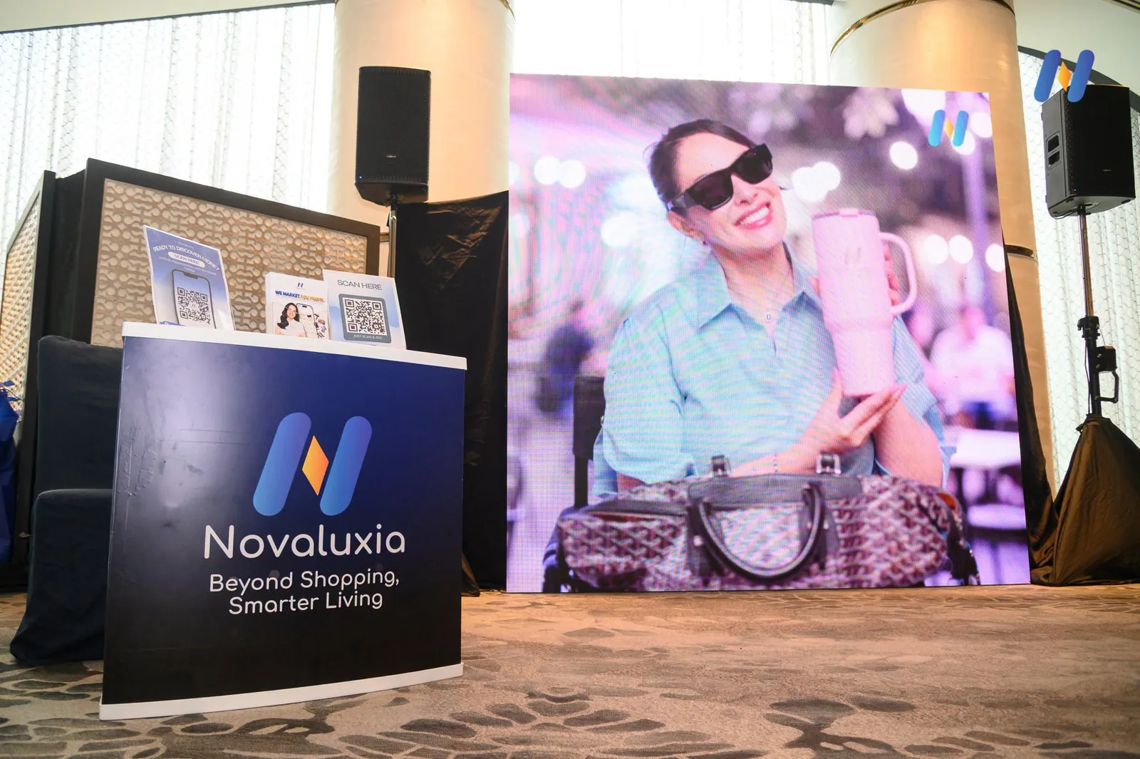 The Novaluxia booth sign reading Beyond Shopping, Smarter Living above a glowing app display at the retail expo